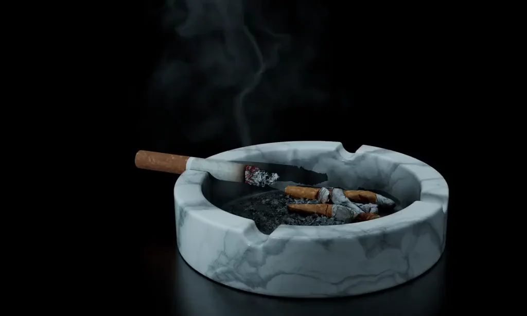 A smouldering cigarette resting on a marble ashtray, smoke curling up