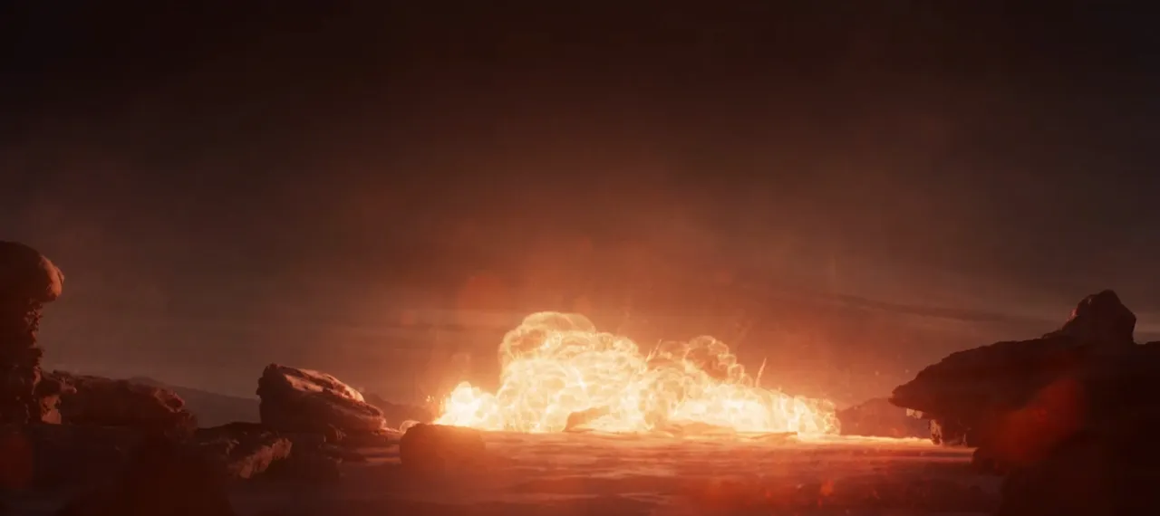 A huge orange explosion rising from a dusty, rocky desert at dusk