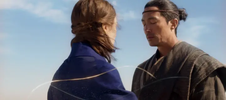 Thin glowing curves drifting around a man and a woman in a desert wind